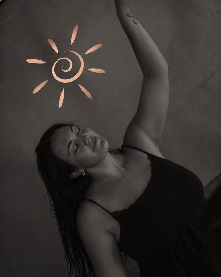 Rachelle with eyes closed and one arm reaching up beneath the H.E.R. Unbound sun